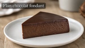 Tranche de flan au chocolat noir sur une assiette blanche, avec une texture intérieure crémeuse et une surface lisse et brillante, et le texte « Flan chocolat fondant » affiché en surimpression.
